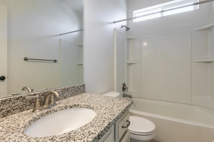 Bathroom vanity featuring a speckled countertop with an undermount sink and brushed nickel faucet