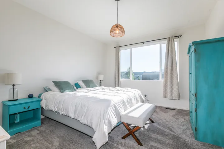 Carpeted room featuring a large window, white walls, and a woven pendant light fixture