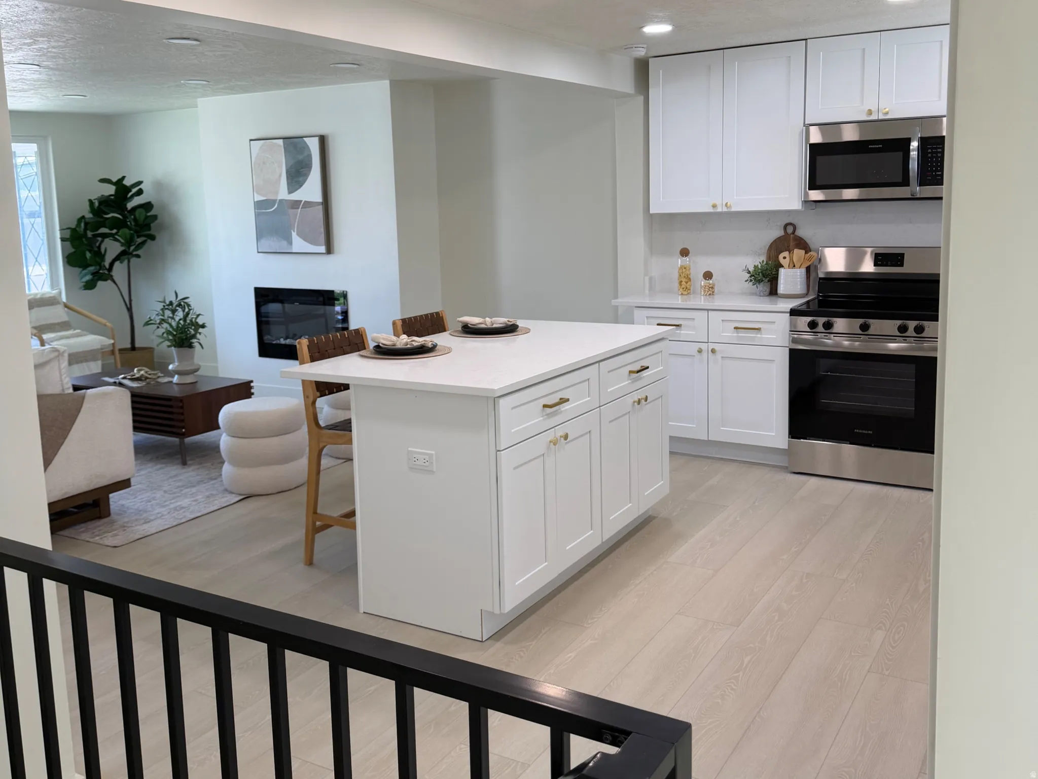 Kitchen featuring stainless steel appliances, white cabinetry, light wood-style floors, open floor plan, and a kitchen breakfast bar