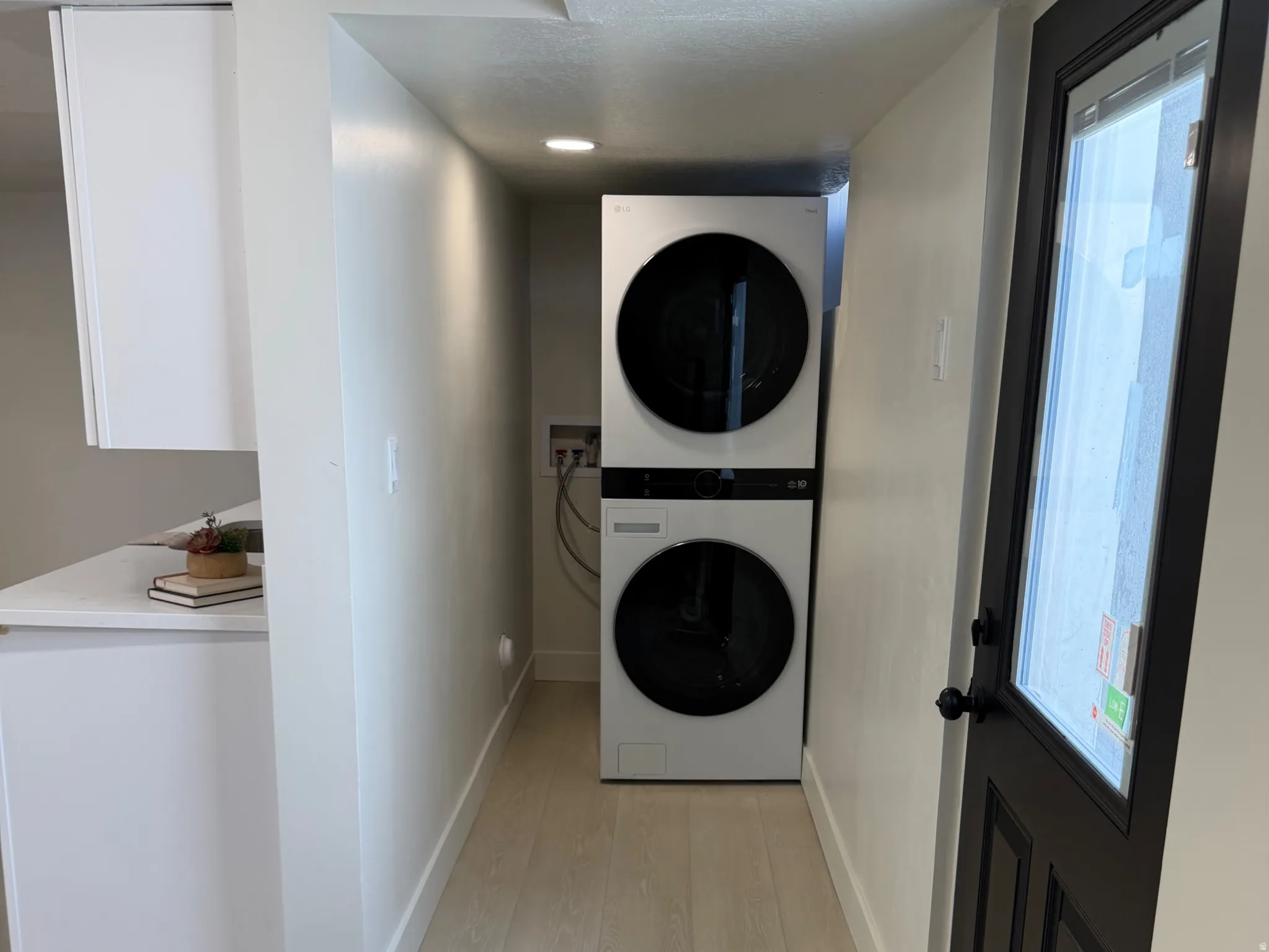 Laundry area featuring light wood-type flooring and stacked washer and dryer