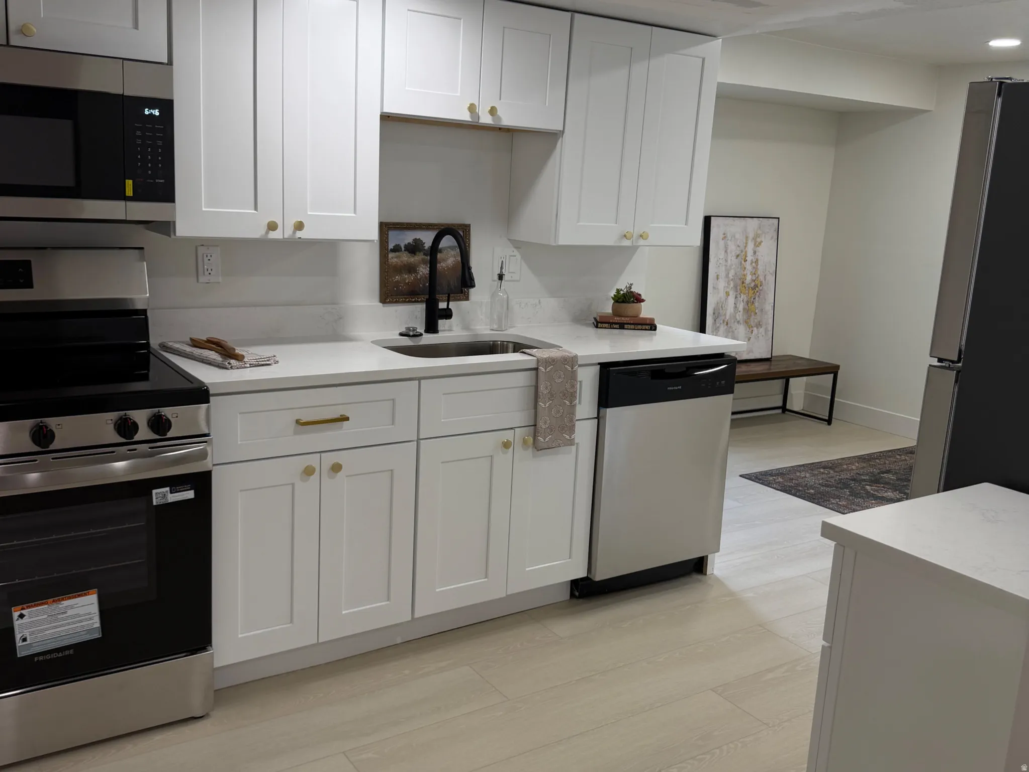 Kitchen with stainless steel appliances, white cabinets, light wood-style floors, light stone counters, and recessed lighting
