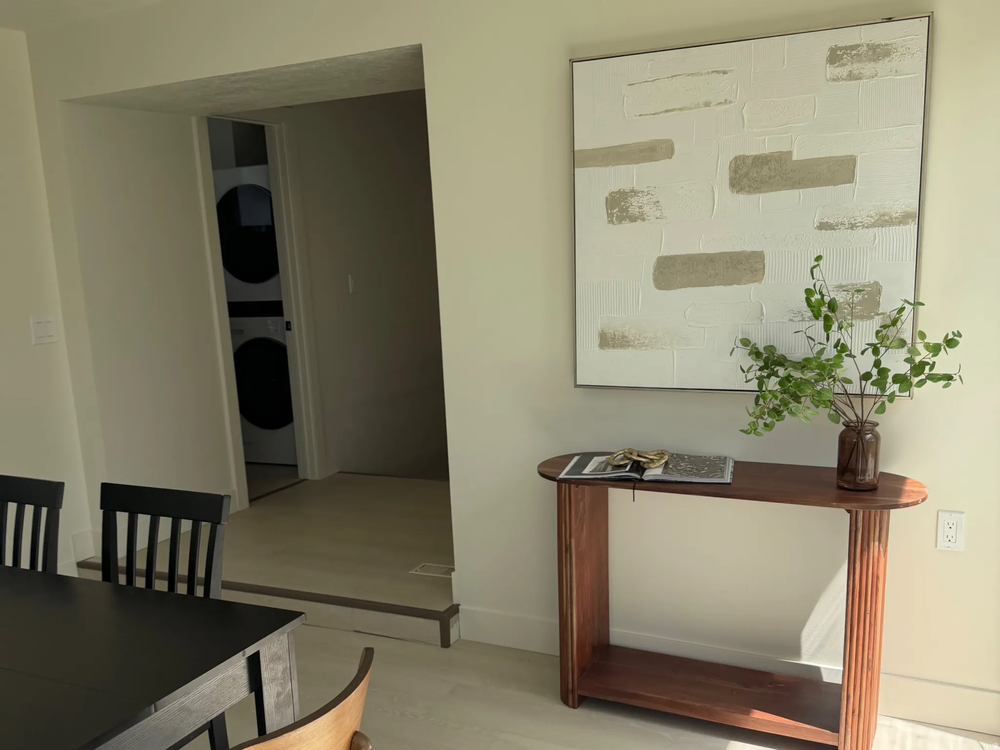 Dining area with light wood-style flooring, stacked washer and clothes dryer, and a textured ceiling