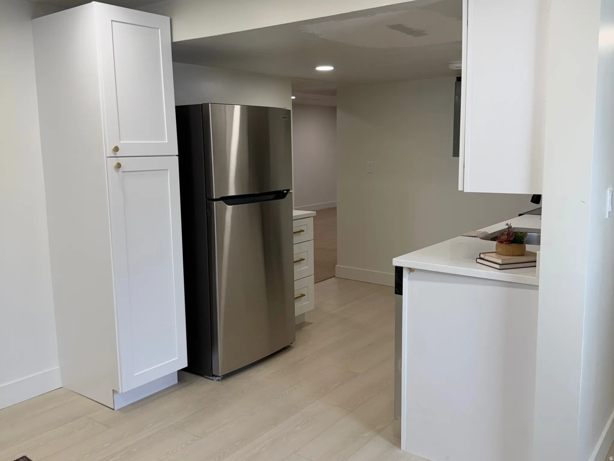Kitchen featuring freestanding refrigerator, white cabinets, recessed lighting, light countertops, and light wood finished floors
