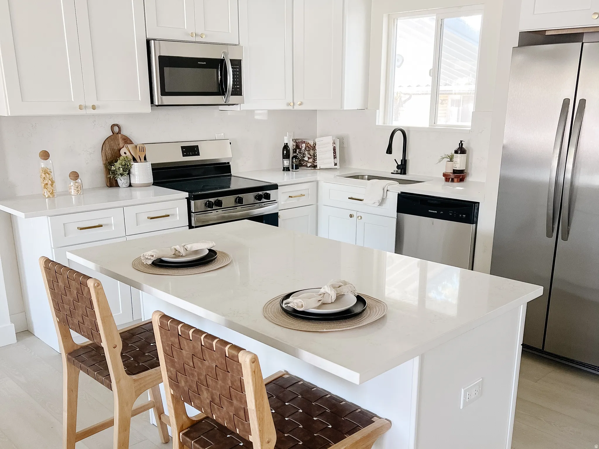 Kitchen with stainless steel appliances, white cabinetry, light wood-style flooring, a center island, and a kitchen breakfast bar