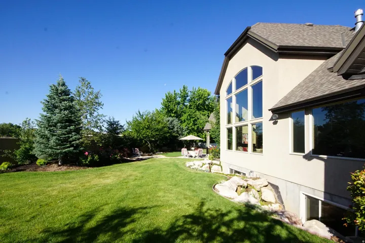 Expansive lawn featuring mature evergreen trees and established landscaping