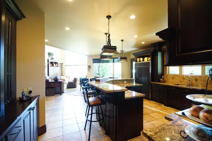 Kitchen featuring dark wood cabinetry, granite countertops, tile flooring, and recessed lighting