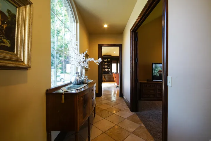 Hallway featuring a large arched window with grid details, diagonal tile flooring, and dark wood trim