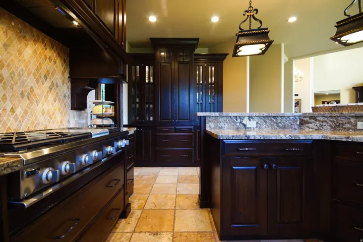 Gourmet kitchen featuring a professional-grade stainless steel range, rich wood cabinetry, granite countertops, and a full tile backsplash