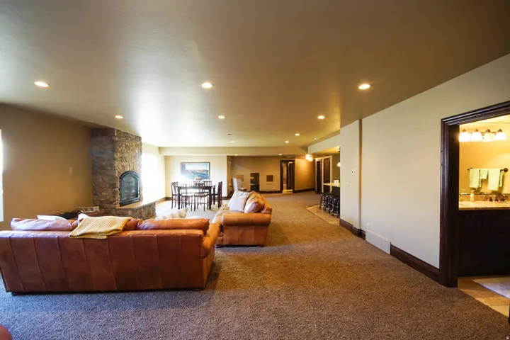 Spacious living area featuring recessed lighting, a stone-clad fireplace, and plush carpet flooring