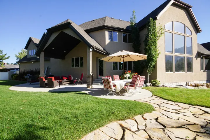 Expansive backyard featuring a manicured lawn, flagstone pathway, and a large multi-pane window wall