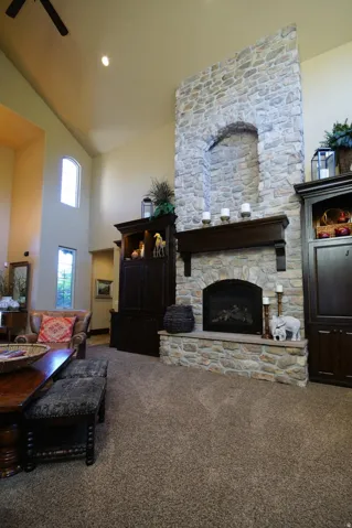 Expansive living area featuring a stone fireplace with a raised hearth, a dark wood mantel, and built-in cabinetry