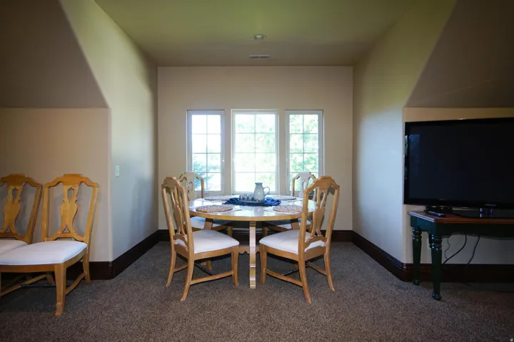 Carpeted room featuring a trio of windows, dark wood-finish baseboards, and neutral wall tones