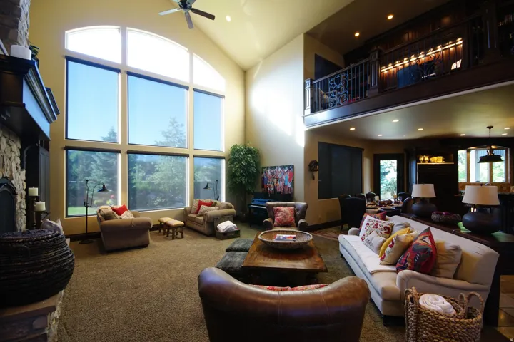 Vaulted great room with expansive picture windows, a stone fireplace, and a second-story balcony overlooking the space