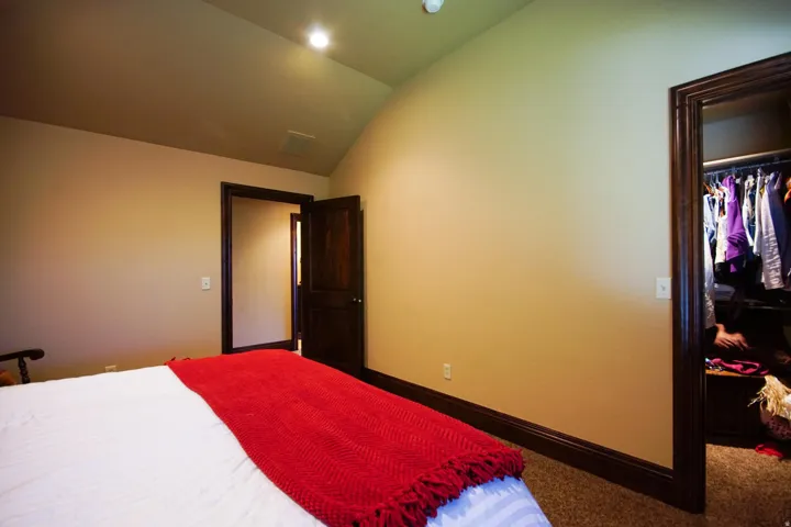 Bedroom featuring a vaulted ceiling with recessed lighting, dark wood-finish trim and doors, and a closet with built-in storage