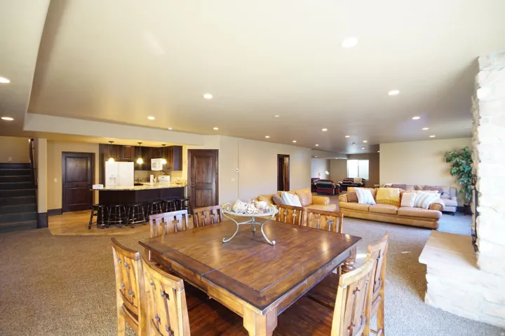 Spacious lower-level living area with recessed lighting, a stone-clad fireplace, and neutral carpeting
