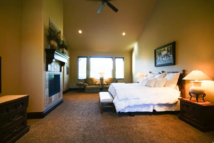 Spacious room featuring vaulted ceilings, recessed lighting, and a prominent fireplace with a stone surround and dark wood mantel