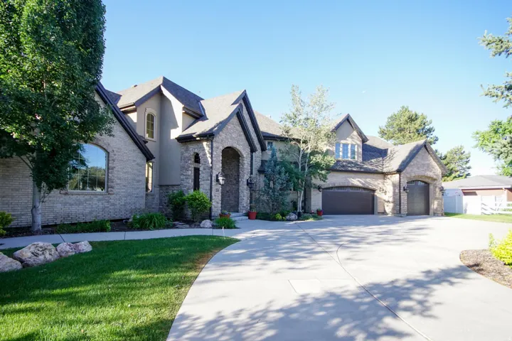 Stately home featuring a multi-gabled roofline, stone and stucco exterior, arched entry, arched windows, and a multi-car garage with dark wood-finish doors