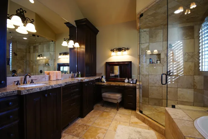 Spacious bathroom featuring a dual vanity with granite countertops, rich wood cabinetry, and a substantial wall-mounted mirror