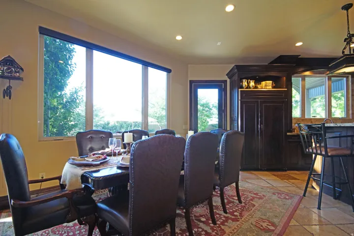 Dining area with a large picture window, recessed lighting, tile flooring, and dark wood built-in cabinetry featuring an integrated refrigerator