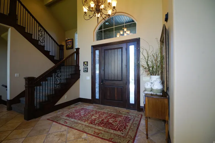 Grand foyer featuring a dark wood front door with sidelights, an arched transom window, and a decorative chandelier
