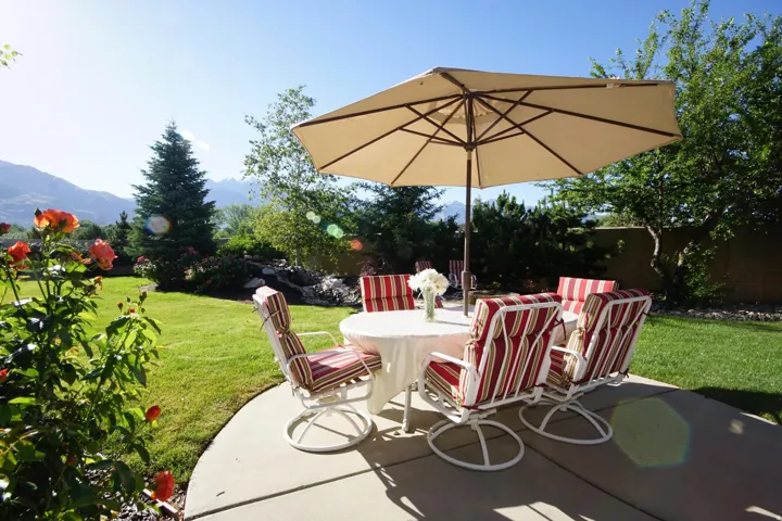 Curved concrete patio with a lush lawn, mature landscaping, and mountain scenery
