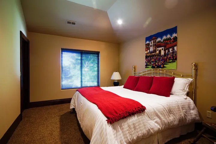 Carpeted bedroom featuring a vaulted ceiling with recessed lighting and a window with blinds