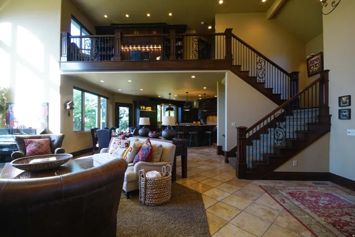 Two-story living area featuring a grand staircase with wrought iron balusters, wood-finish treads, and carpeted risers