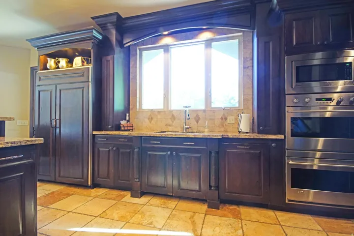 Custom cabinetry and an integrated paneled refrigerator complement the built-in stainless steel double ovens and microwave