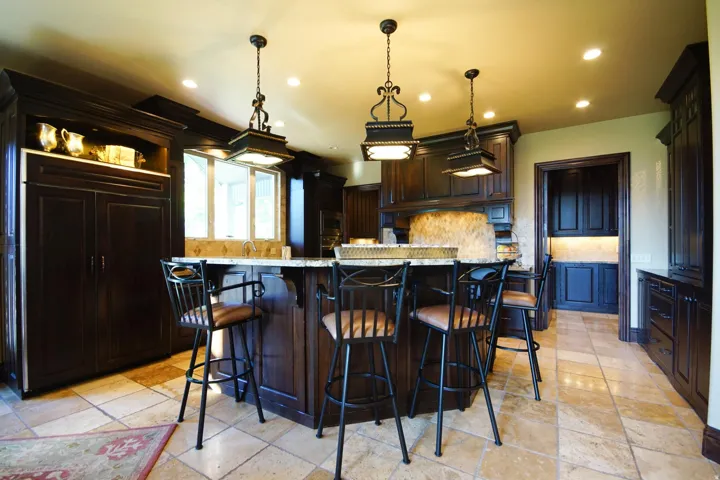 Kitchen featuring dark wood cabinetry, a central island with a light-toned countertop, and recessed lighting