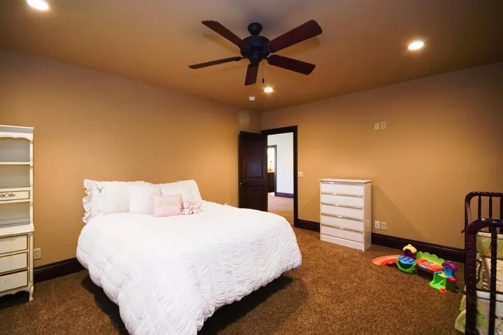 Spacious room featuring plush brown carpeting, dark wood-finish trim, and recessed lighting