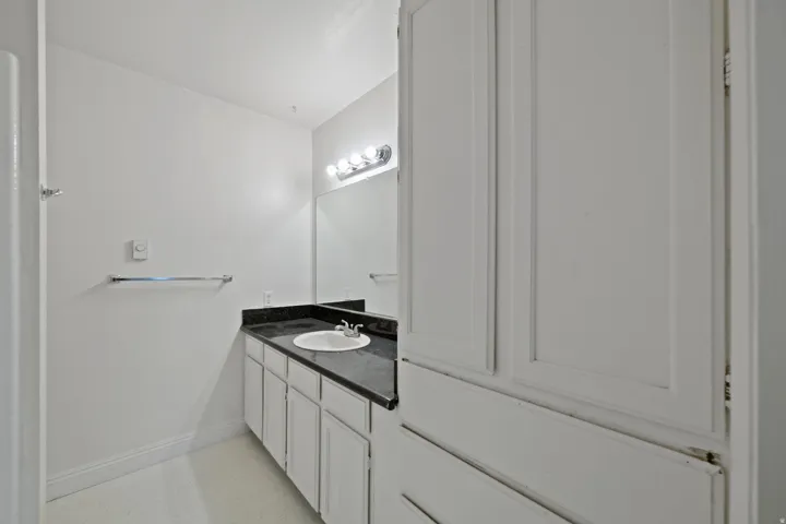 Bathroom vanity with an integrated sink, dark countertop, and overhead lighting