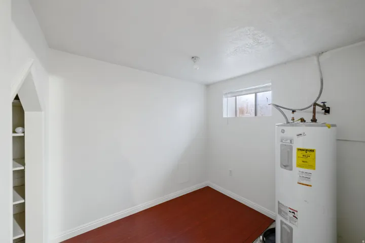 Utility space with white walls, wood-finish flooring, and a water heater