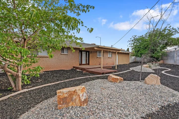 Landscaped backyard featuring decorative rock, natural boulders, and mature trees