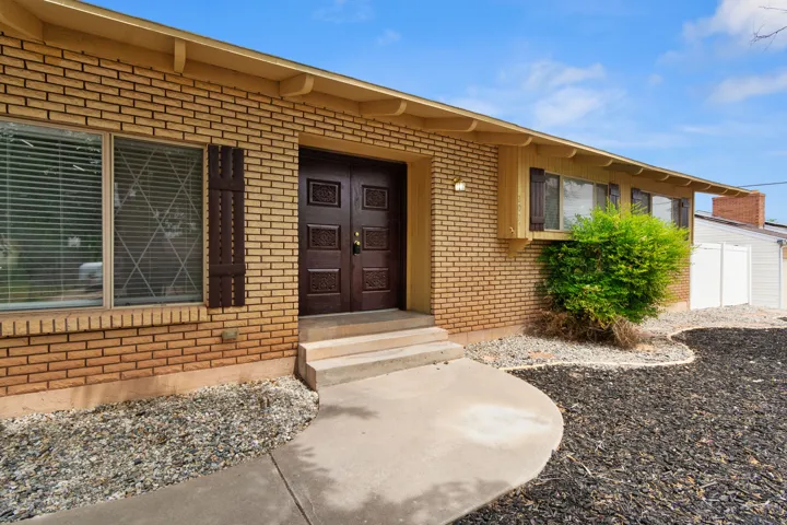 Brick exterior featuring a concrete walkway, double entry doors, exterior shutters, and a decorative window security grill