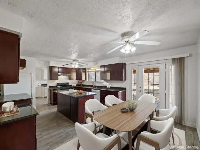 Open-concept kitchen and dining area featuring rich wood cabinetry, dark countertops, and wood-finish flooring