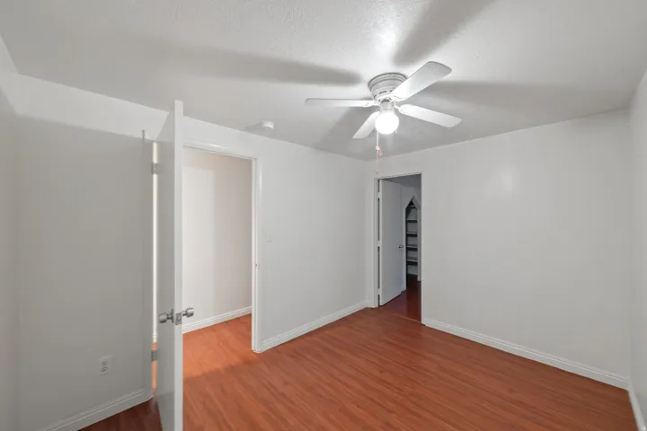 Room featuring wood-finish flooring, white baseboards, and a ceiling fan with integrated lighting