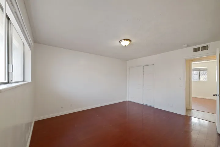 Spacious interior featuring rich wood-finish flooring, white walls, and a large window with a deep sill