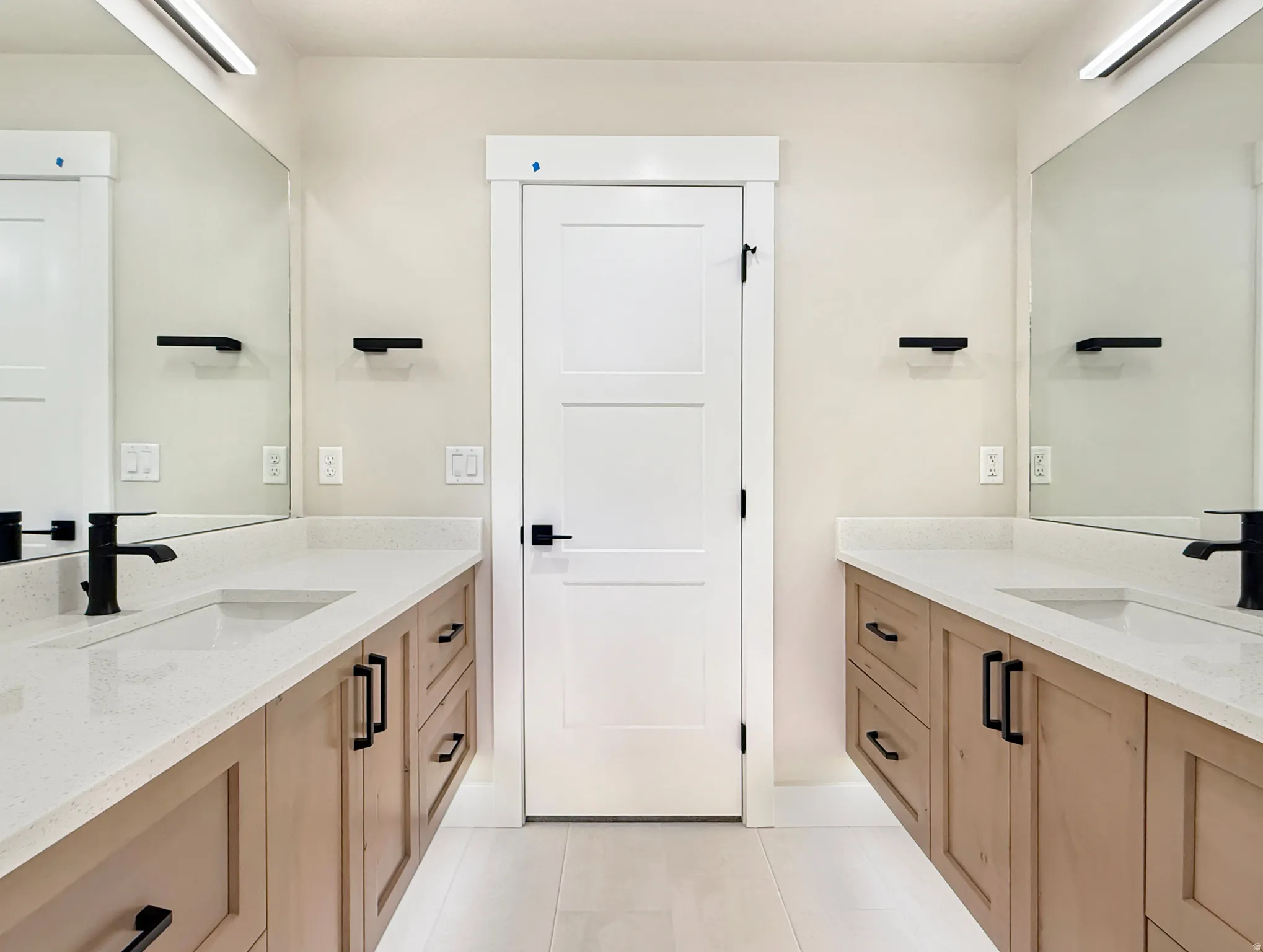 Dual vanity featuring light wood-finish cabinetry and white countertops
