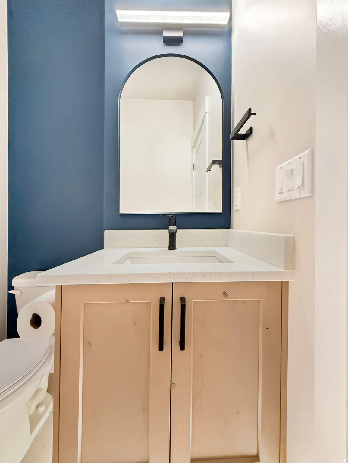 Vanity featuring a light wood-finish cabinet with matte black hardware, integrated sink, and light-toned countertop