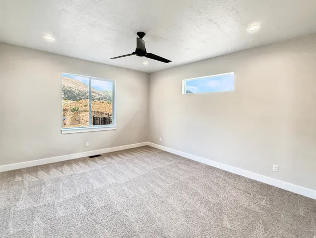 Spacious room featuring neutral carpeting, a contemporary black ceiling fan, and recessed lighting