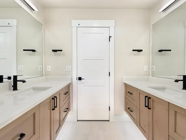 Dual vanity featuring light wood-finish cabinetry and white countertops