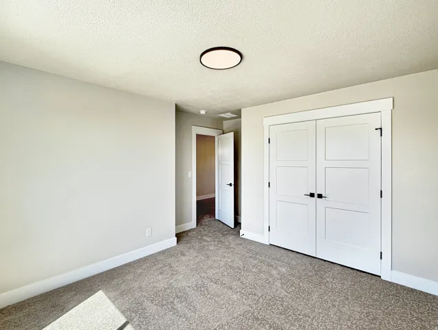 Carpeted room featuring a ceiling-mounted light fixture, light gray walls, white baseboards, and white paneled double doors with black hardware