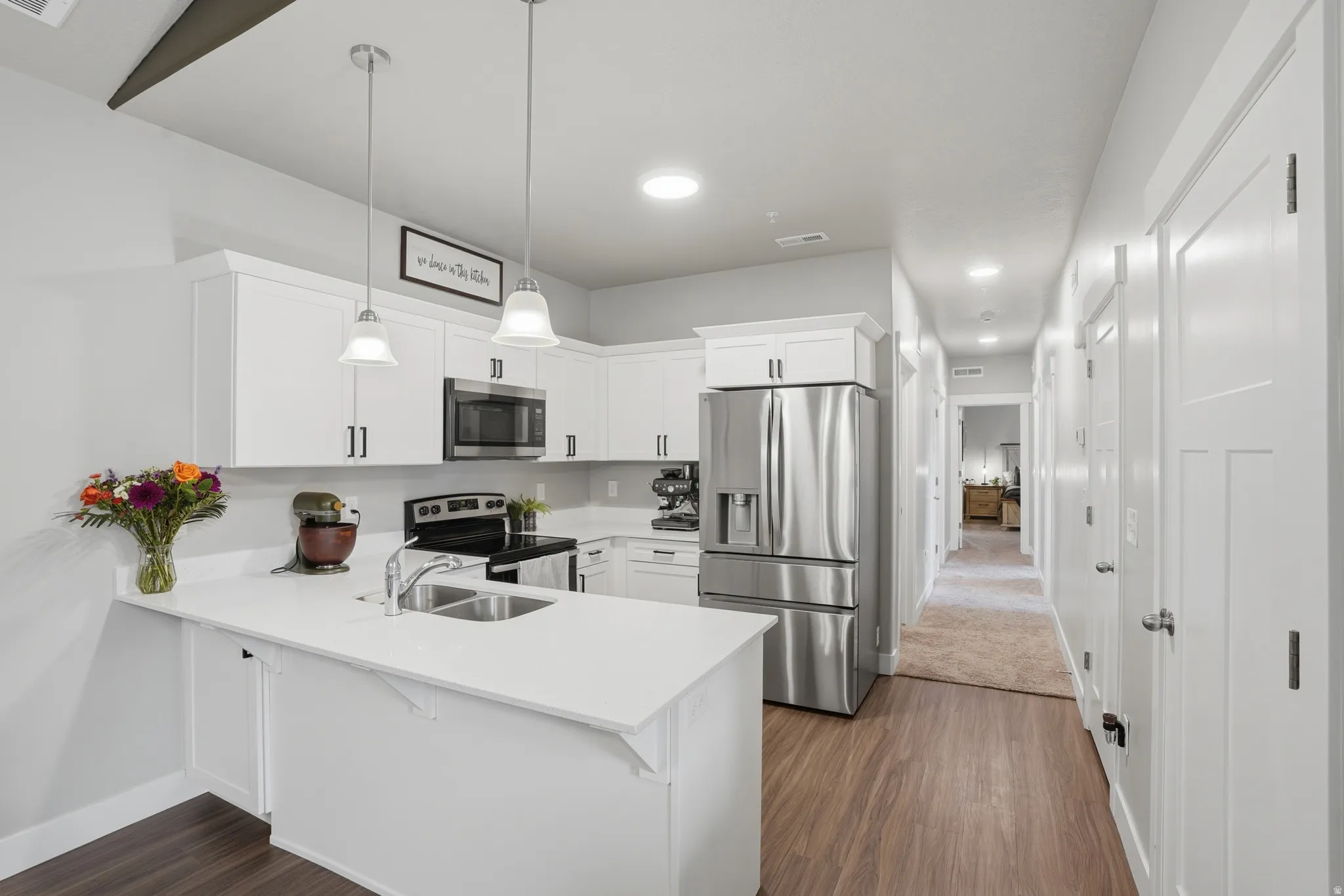 Modern kitchen featuring white cabinetry, stainless steel appliances, a double basin sink, recessed lighting, and wood-finish flooring