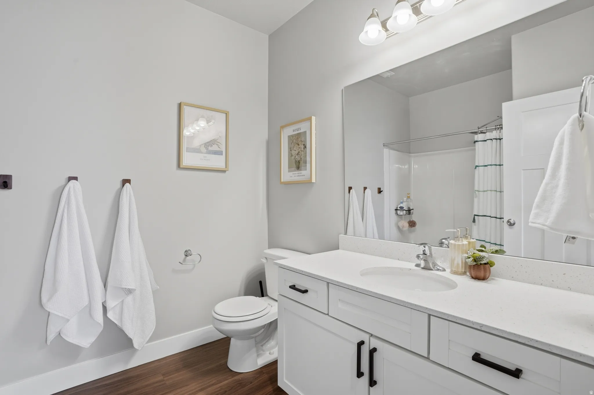 Bathroom with a white vanity featuring a speckled countertop, integrated sink, and matte black hardware