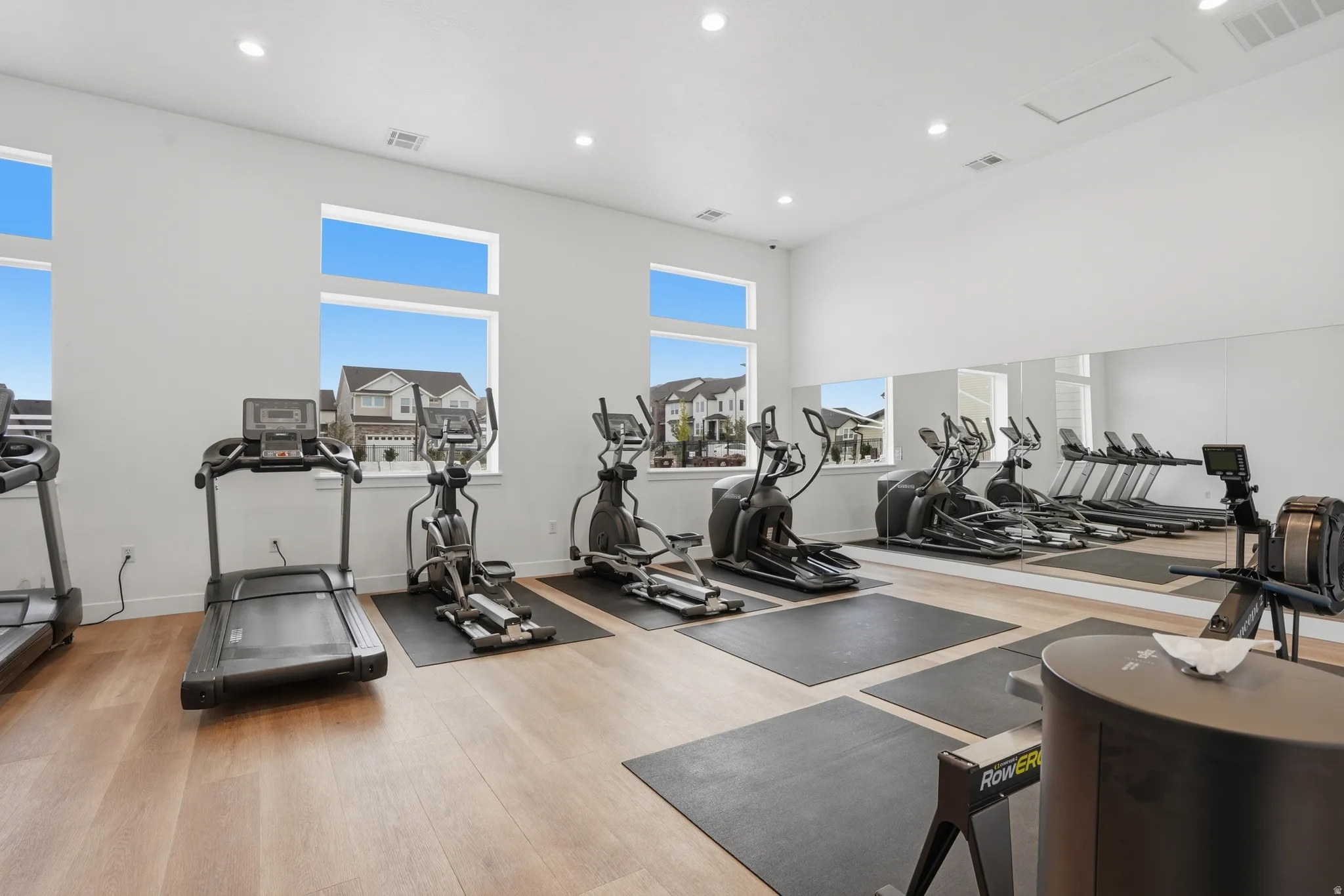Fitness room featuring wood-finish flooring, ample natural light from multiple windows, recessed lighting, and mirrored walls