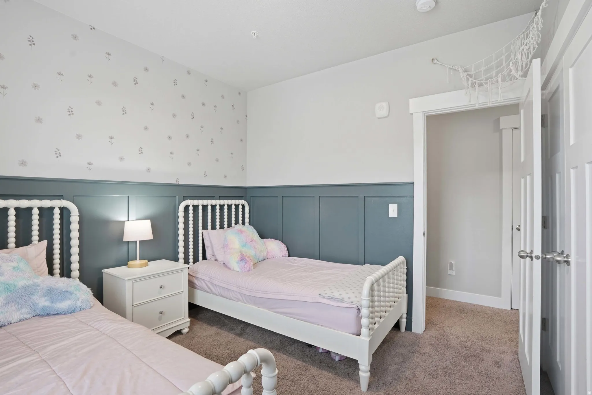 Bedroom featuring a paneled accent wall, neutral carpeting, white trim, and a white interior door