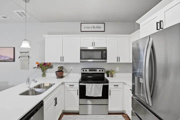 Modern kitchen featuring white cabinetry, stainless steel appliances, light countertops, and a stainless steel double-basin sink