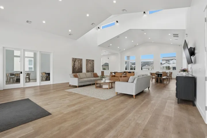 Spacious common area featuring vaulted ceilings with high windows, recessed lighting, and wood-finish flooring