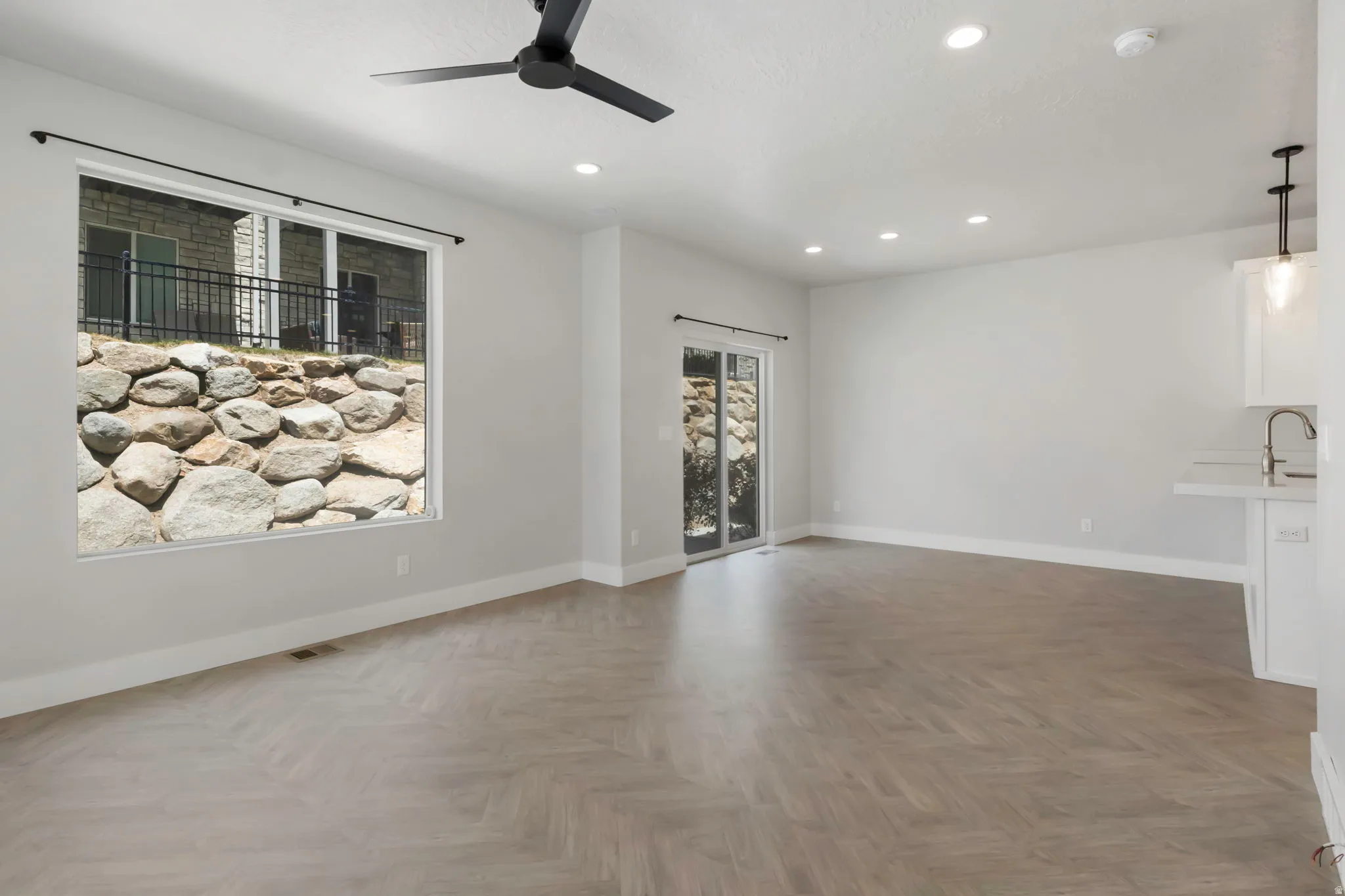 Spacious living area featuring wood-finish flooring in a herringbone pattern and recessed lighting