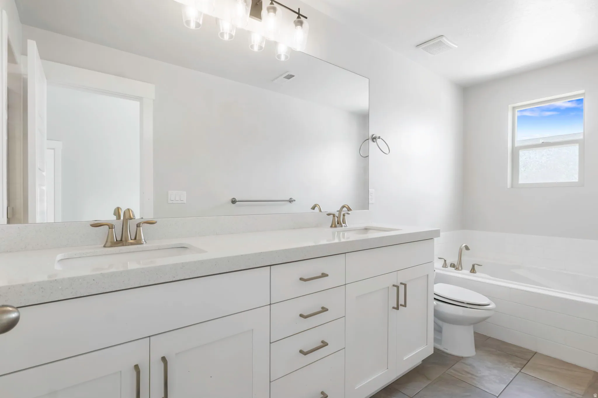 Bathroom with a double vanity featuring white shaker cabinetry, light-toned countertops, and brushed nickel hardware